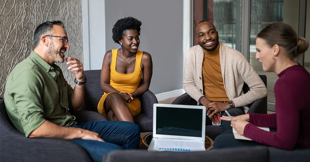 A group of people sitting around a laptop screen.